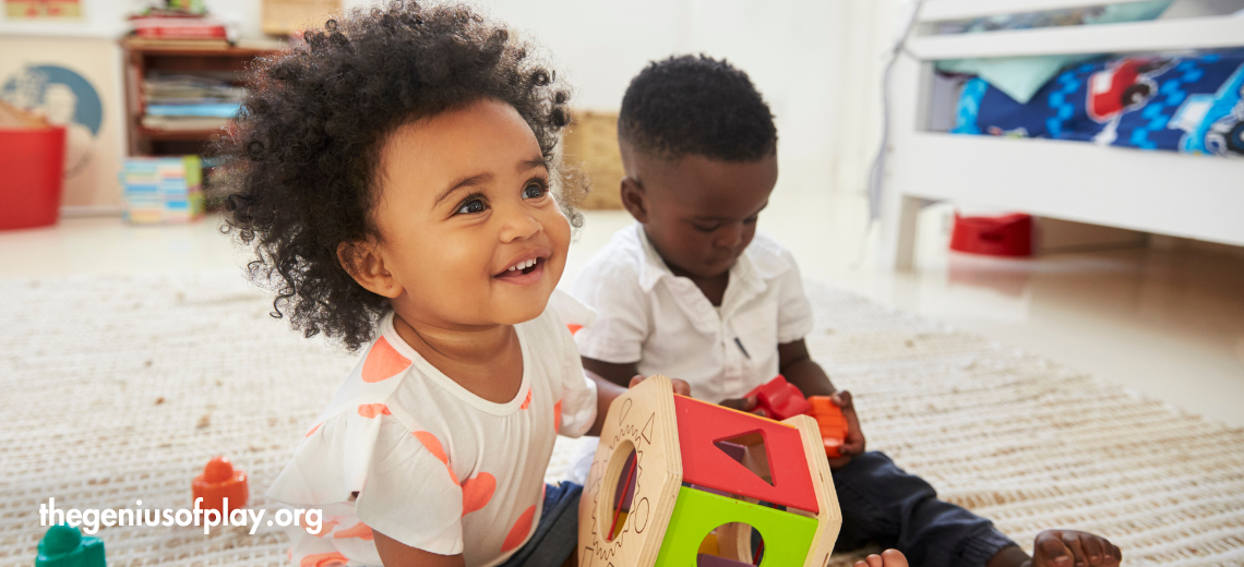 young African American girl and boy toddler playing together with blocks in a playroom