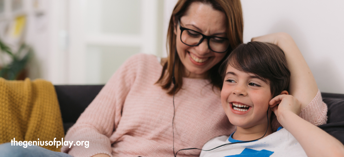 Mother and young son wearing headphones to listen to a podcast together 