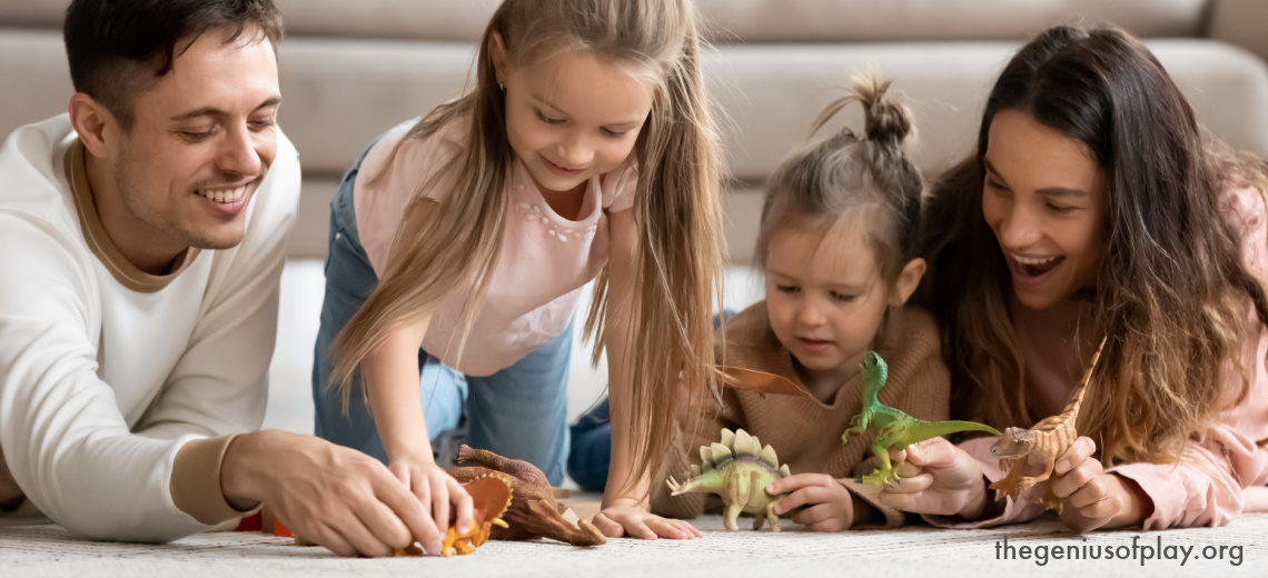 happy parents and young daughters playing with dinosaurs on the floor